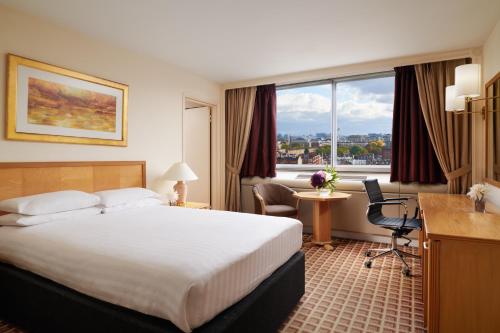 Cette chambre comprend un lit, un bureau et une fenêtre. dans l'établissement Copthorne Tara Hotel London Kensington, à Londres