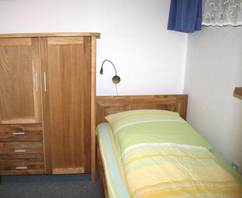 ヴィーク・アウフ・フェールにあるFewo-am-Museumのベッドルーム1室(ベッド1台付)、木製キャビネットが備わります。
