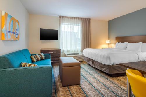 a hotel room with a bed and a couch and a table at MainStay Suites Newnan Atlanta South in Newnan