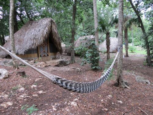 a hammock in front of a hut in the woods at Bel-Há Ecoparque in El Naranjo