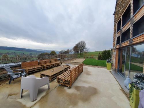 a patio with wooden benches and a white chair at Gîte Le Rivage in Stavelot