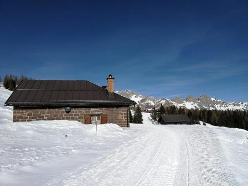 a brick building in the snow with a snow covered road at Baita Casera Caviazza in Falcade