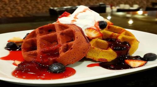 a white plate with waffles and berries and whipped cream at Holiday Inn Hotel & Suites Gateway by IHG in Williamsburg