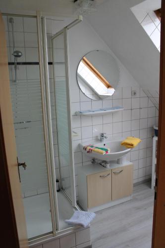 ein Bad mit einem Waschbecken und einer Glasdusche in der Unterkunft Wohnung 2 in Oevenum