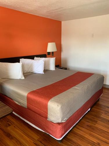 Cama grande en habitación con paredes de color naranja en Scottish Inns and Suites- Bordentown, NJ, en Bordentown