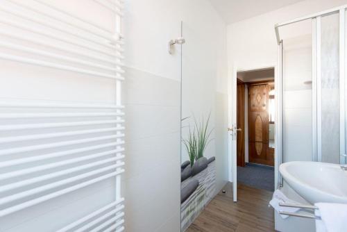 ein Badezimmer mit weißen Wänden, einem Waschbecken und einem Spiegel in der Unterkunft Kapitänshaus Lassen - Zimmer Penelope in Westerland