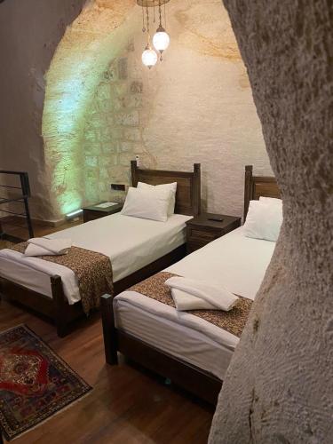 a bedroom with two beds and a stone wall at Ürgüp Inn Cave Hotel in Urgup