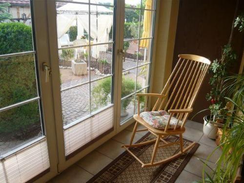 einen Schaukelstuhl auf einer Veranda neben einem Fenster in der Unterkunft Ferienwohnungen Roder - Ferienwohnung I in Freiburg im Breisgau