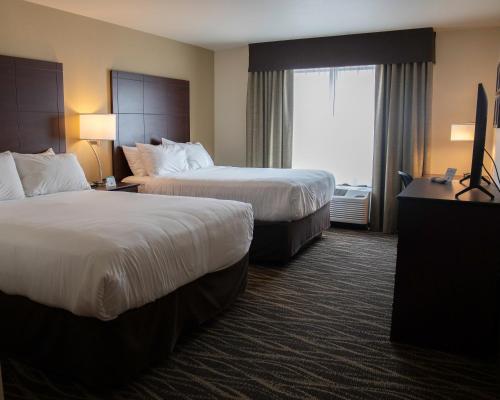 a hotel room with two beds and a window at Cobblestone Hotel & Suites - Two Rivers in Two Rivers