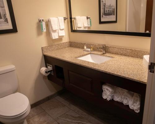 a bathroom with a sink and a toilet and a mirror at Cobblestone Hotel & Suites - Two Rivers in Two Rivers