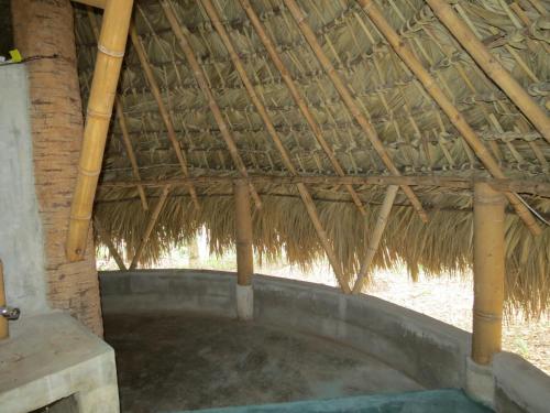 a building with a straw roof with a hot tub at Bel-Há Ecoparque in El Naranjo