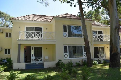 a large yellow house with a balcony at Forest Lagoon Apartamento 6 in Punta del Este