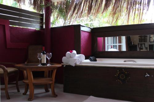 Aquabarra Boutique Hotel & Spa في بوزيوس: حمام مع حوض استحمام وطاولة مع كأس من النبيذ