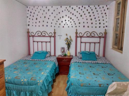 1 dormitorio con 2 camas y edredones azules en Escocie Quito Colonial, en Quito