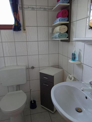 a white bathroom with a toilet and a sink at Haus Seerobbe-Erdgeschosswohnung in Fehmarn