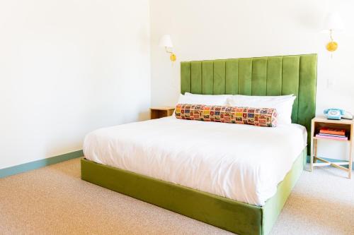 a bed with a green headboard in a bedroom at Bradford House, a Member of Design Hotels in Oklahoma City
