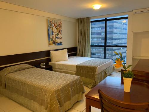 a hotel room with two beds and a table and a window at America Towers Hotel in Salvador