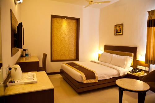 a hotel room with a bed and a table at Hotel Prince Gardens in Coimbatore