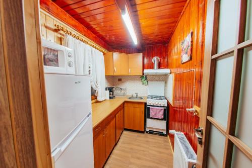 a kitchen with wooden cabinets and a white refrigerator at Cabana Mihai in Sovata