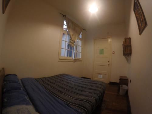 a small bedroom with a bed and a window at Lemuria Hostel in Valparaíso