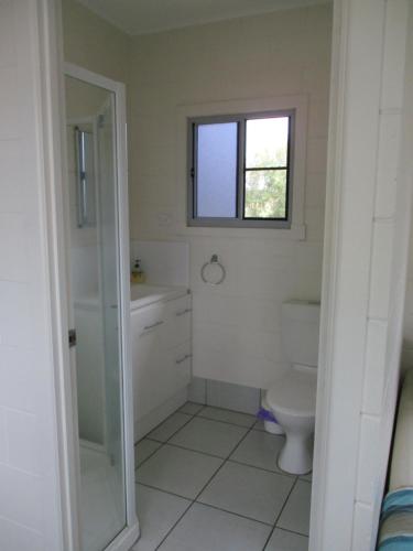 a bathroom with a toilet and a window at Ingham Tourist Park in Ingham