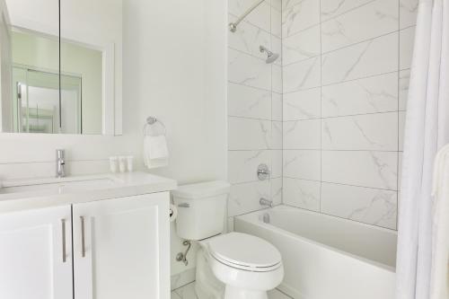 a white bathroom with a tub and a toilet and a sink at Sonder The Elm in Toronto