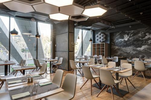 a restaurant with tables and chairs and a wall of windows at Sky Loft Hotel Kyiv by Rixwell International in Kyiv