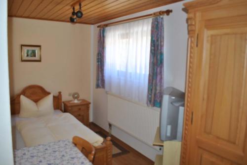 a bedroom with a bed and a television and a window at Zur Alten Dampfsäge - Gasthaus-Pension Weber in Lindberg