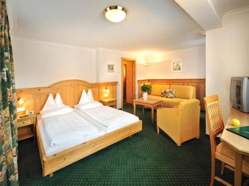 a hotel room with a large bed and a couch at Hotel zum Hirschen Zell am See in Zell am See