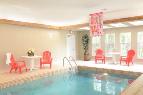 una piscina con sillas rojas, una mesa, una mesa y un sillón en Eagle Harbor Inn, en Ephraim