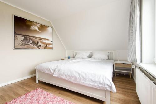 ヘルヌムにあるFerienwohnung-LUVの白いベッドルーム(ベッド1台付)が備わります。壁に絵が描かれています。