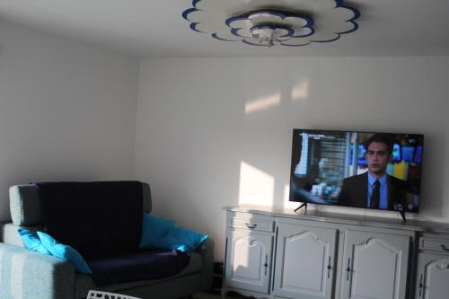 une télévision installée au-dessus d'un meuble avec une chaise dans l'établissement Parcappart, à Voiron