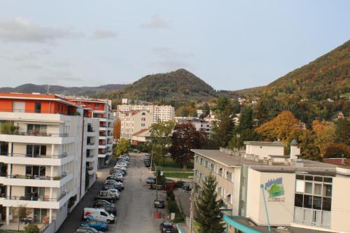 a city street with buildings and mountains in the background at Parcappart in Voiron