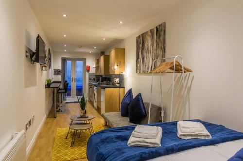 a bedroom with a blue bed and a kitchen at Long Row Apartments in Nottingham City Centre in Nottingham