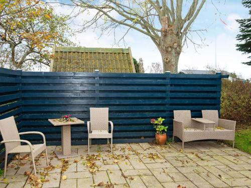 um pátio com cadeiras, uma mesa e uma parede azul em 5 person holiday home in Egernsund em Egernsund