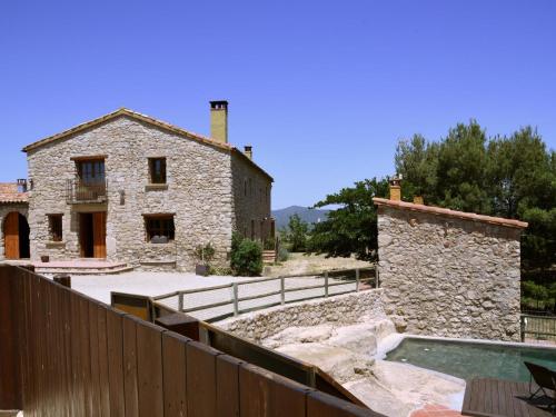 Castellolí的住宿－Belvilla by OYO Cal Sant Miquel，一座古老的石头房子,前面设有一个游泳池