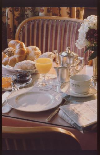 a table with plates of food and a glass of orange juice at Unser kleines Hotel Café Göbel in Laubach