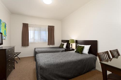 a hotel room with two beds and a television at Redcliffe Motor Inn in Redcliffe