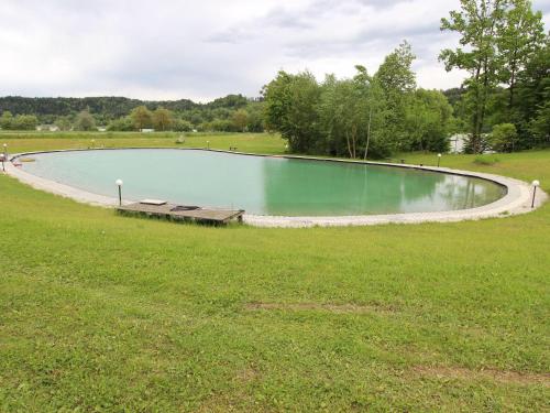 una piscina de agua con un banco en un campo en Mobile home near Lake Klopeiner See en Sankt Kanzian