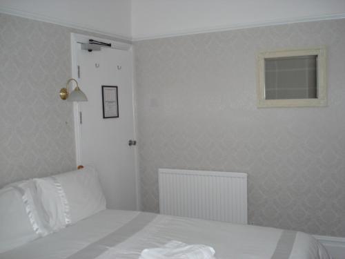 
a bedroom with a white bed and white walls at Invernook in Newquay
