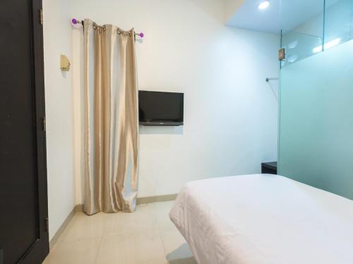 Schlafzimmer mit einem Bett und einem Flachbild-TV in der Unterkunft Puri Maju Hotel in Jakarta