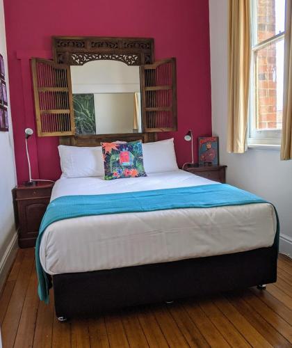 a bedroom with a large bed with pink walls at The Empire Hotel Deloraine in Deloraine