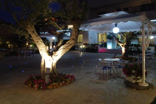 a tree in a courtyard with a table and chairs at Hotel Costa Verde in Tortoreto Lido