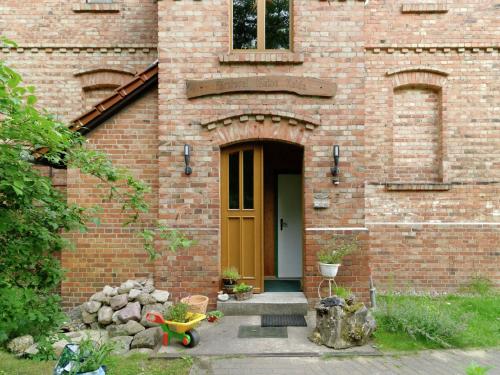 a brick house with a brown door and a yellow wheelbarrow at Apartment with garden in F rstenwalde in Fürstenwalde-West