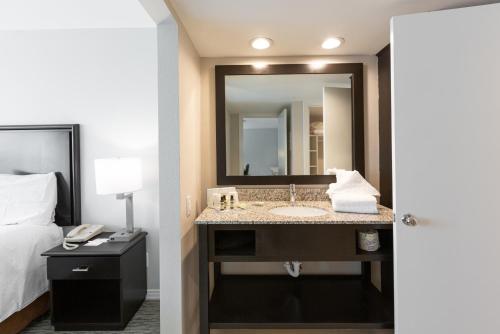 a bathroom with a sink and a bed and a mirror at Value Suites Extended Stay - Arlington in Arlington