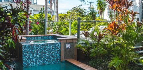 a swimming pool in a garden with plants at Heritage Cairns Hotel in Cairns