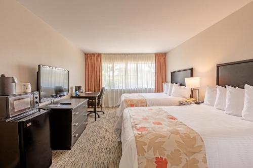 a hotel room with two beds and a flat screen tv at Value Suites Extended Stay - Arlington in Arlington