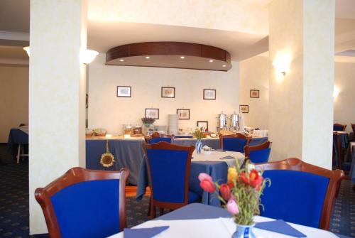 jadalnia ze stołami i niebieskimi krzesłami w obiekcie Hotel Mediterraneo w mieście Civitavecchia