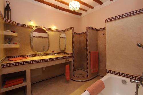 a bathroom with a tub and two mirrors on the wall at Riad Soumia in Marrakesh