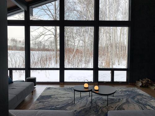a living room with two tables and a large window at Hakobune Niseko - 8-room Chalets & 2-room Apartments in Niseko